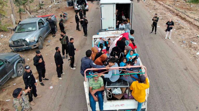 This aerial view shows a truck carrying evacuating members of the Bedouin community stopping at a checkpoint set up by Syrian government forces along a road in Taarah, in Syria’s southern Sweida province on the way to Daraa, on July 21, 2025. Calm returned to southern Syria’s Sweida province on July 20, a monitor and AFP correspondents reported, after a week of sectarian violence between Druze fighters and rival groups that killed more than 1,100 people. - Rami al SAYED / AFP