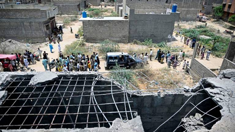 Residents gather as police personnel inspect the site where an alleged drone was shot down in Karachi on May 8, 2025. Pakistan’s army said on May 8, it shot down 25 Indian drones, a day after the worst violence between the nuclear-armed rivals in two decades. AFPpix