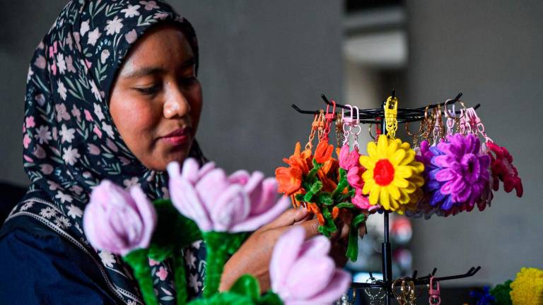 Siti Amirah Pilus melakukan sentuhan akhir pada bunga hiasan yang dibentuk dari dawai baldu di kediamannya, baru-baru ini -BERNAMA