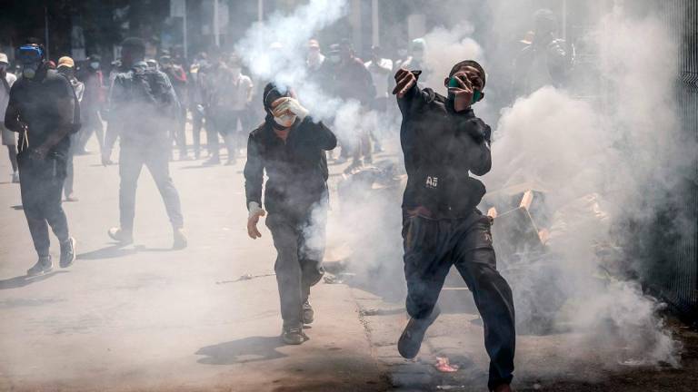 A protester throws a teargas canister back at police officers during clashes with Malagasy security forces during a strike calling for constitutional reforms and the resignation of President Andry Rajoelina, in Antananarivo, on October 9, 2025. - Luis TATO / AFP
