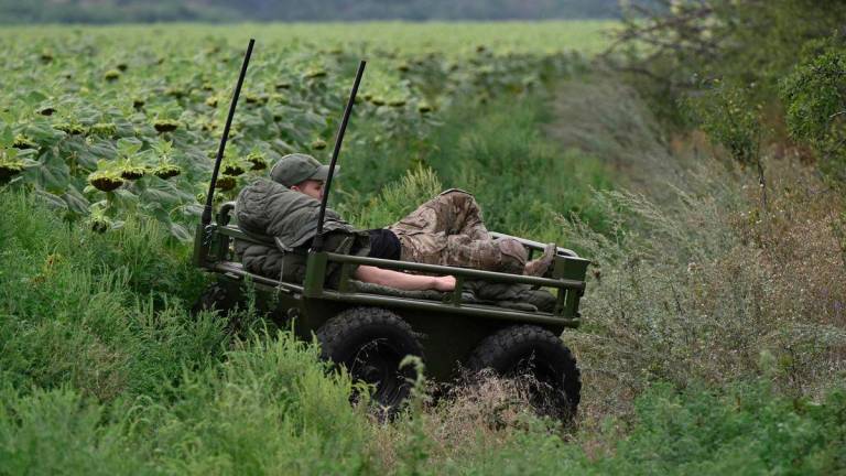 A Ukrainian serviceman, 24, with call sign Bot from the 5th Separate Assault Brigade, rests on the platform of an unmanned ground vehicle during a demonstration of its capabilities on a training ground at an undisclosed location in eastern Ukraine on August 11, 2025, amid the Russian invasion of Ukraine. (Photo by Genya SAVILOV / AFP)