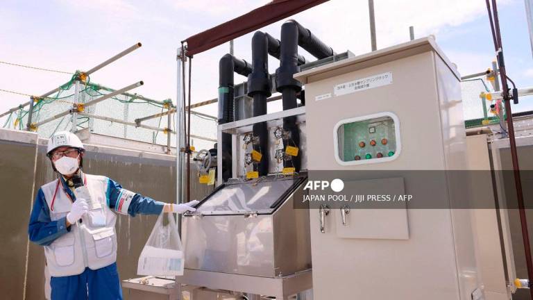 An official demonstrates an equipment for sampling water to analyze the concentration of radioactive tritium before discharging diluted treated water, as part of the facility for the releasing the treated water of the Tokyo Electric Power Company Holdings Inc. (TEPCO) Fukushima Daiichi Nuclear Power Plant in Okuma, Fukushima prefecture on August 27, 2023. - JAPAN POOL / JIJI PRESS / AFP
