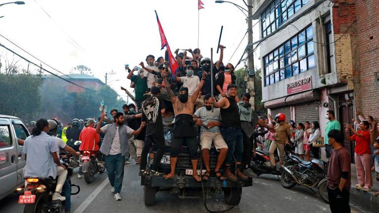 Protesters carry Nepal’s national flag as they ride a police truck outside the President House in Kathmandu on September 9, 2025, a day after demonstrations over social media prohibitions and corruption by the government. - Prabin RANABHAT / AFP