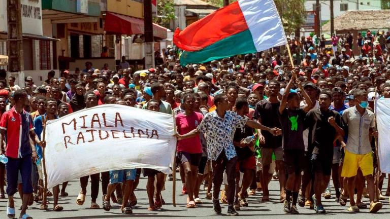 Protesters carry a Madagascar flag and a banner during an anti-government protest in Antsiranana on October 1, 2025. (Photo by FITA / AFP)