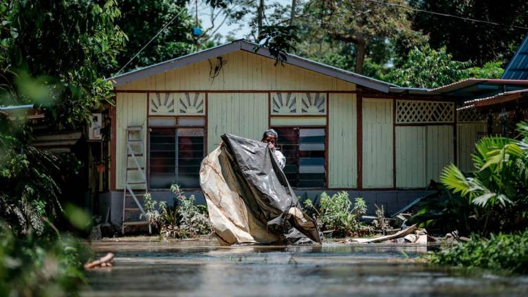 Seorang penduduk, Aileen Hana Abdullah mengemas sekitar luar rumahnya yang dinaiki air ketika tinjauan fotoBernama di Kampung Paya Embun, Pekan Nenas hari ini. - fotoBERNAMA