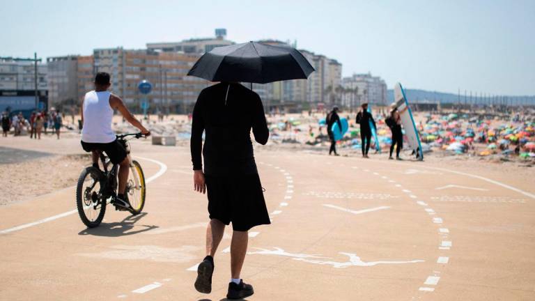 A man uses an umbrella to shield himself from the scorching sun during the first heatwave of the year in Lisbon, on June 29, 2025. Starting this weekend southern Europe will once again face extreme temperatures exceeding 40°C. - CARLOS COSTA / AFP
