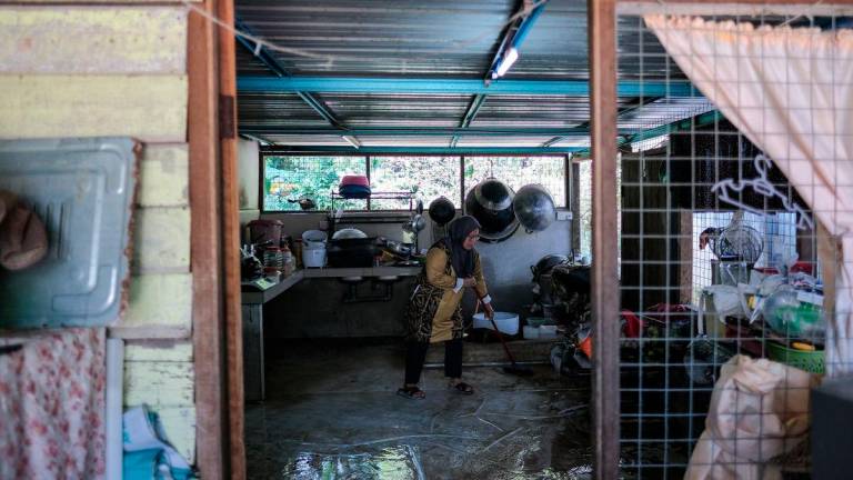 Seorang penduduk Norhayati Ariffin melakukan kerja-kerja pembersihan selepas kediamannya dilanda banjir semalam ketika tinjauan fotoBernama di Kampung Melayu Raya, Pekan Nenas hari ini-fotoBERNAMA