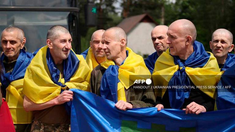 This handout photograph taken and released by the Ukrainian Presidential Press Service on June 14, 2025, shows Ukrainian prisoners of war (POWs) wrapped with Ukrainian national flags posing for a photograph following an exchange of prisoners. - AFP PHOTO / UKRAINIAN PRESIDENTIAL PRESS SERVICE