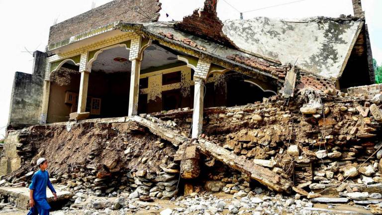 A boy walks past a damaged house a day after flash floods in the Buner district of the monsoon-hit northern Pakistan’s mountainous Khyber Pakhtunkhwa province on August 16, 2025. Rescuers were struggling to retrieve bodies from debris after flash floods triggered by heavy monsoon rains across northern Pakistan killed at least 321 people in the past 48 hours, authorities said on August 16. Photo by Hasham AHMED / AFP