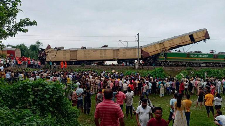 People look on at the site of a collision between an express passenger train and a goods train in Nirmaljote, near Rangapani station in India's West Bangal state on June 17, 2024. - AFPPIX