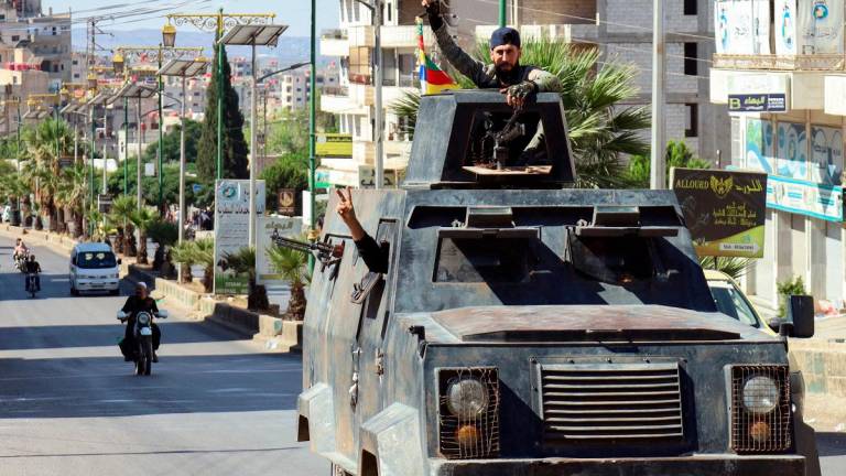 Syrian Druze fighters flash the victory sign as they ride in an armoured vehicle, after Syrian forces pulled out of the southern Sweida governorate, on July 17, 2025. The Druze heartland Sweida has been gripped by deadly sectarian bloodshed since July 13, with hundreds reportedly killed in clashes pitting Druze fighters against Sunni Bedouin tribes and the army and its allies. - Shadi AL-DUBAISI / AFP