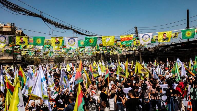 Syrian Kurds lift placards and flags during a rally calling for an autonomous administration and Kurdish rights in Syria’s predominantly-Kurdish northeastern city of Qamishli on September 17, 2025. - Delil SOULEIMAN / AFP