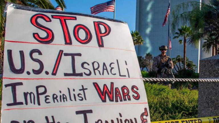 US Marines watch as protesters hold signs during a “No War on Iran” demonstration outside the Wilshire Federal Building in Los Angeles - AFPPIX