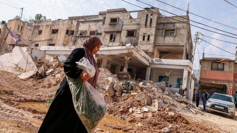 A woman walks past rubble as UN workers conduct rehabilitation works in the vicinity of the damaged UN agency for Palestinian refugees’ UNRWA headquarters at the Nur Shams refugee camp east of Tulkarem in the occupied West Bank - AFPpix