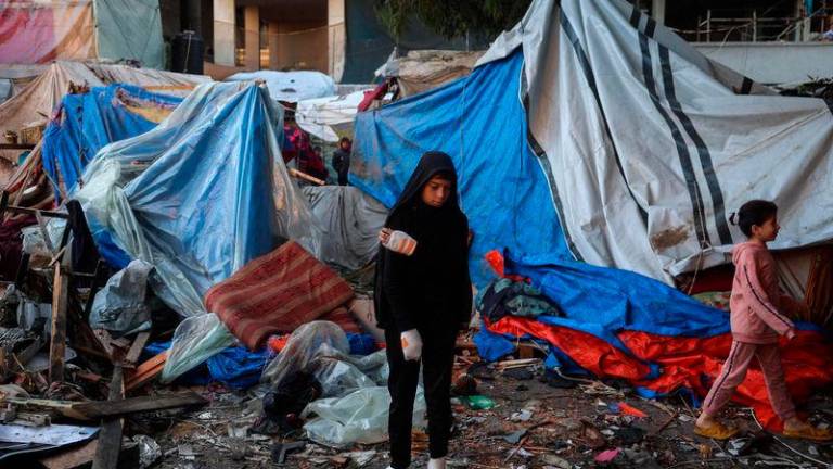 An injured boy stands with other displaced Palestinians amid destroyed tents at a makeshift camp that was hit in Israeli strikes - AFPpix