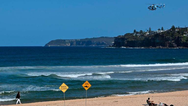 A helicopter scans the ocean as northern Sydney beaches are closed following a suspected shark attack at Long Reef Beach on September 6, 2025. A suspected “large shark” mauled a surfer to death in a rare fatal attack off a Sydney beach on September 6, Australian police and rescuers said, leading to a string of beach closures.