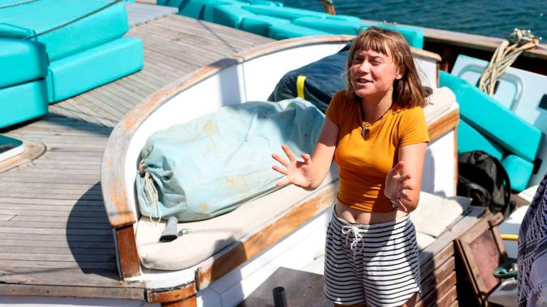 Swedish climate activist Greta Thunberg gestures onboard a boat as a flotilla carrying humanitarian aid and activists prepare to leave for Gaza, in Barcelona on August 30, 2025. A flotilla carrying humanitarian aid and activists, including Swedish climate campaigner Greta Thunberg, is set to depart Barcelona on August 31 to try to “break the illegal siege of Gaza,“ organizers said. (Photo by LLUIS GENE / AFP)