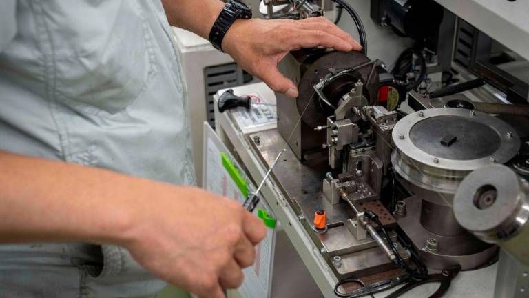 A member of staff works on a production line that manufactures small metal coils at Mitsuwa Electric in Tokyo - Yuichi YAMAZAKI / AFPPix