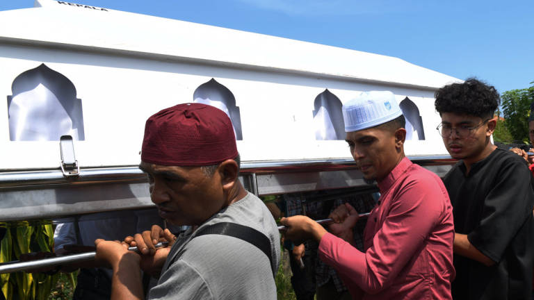 Mohamad Fairiel Danish Firos, 18, (right) and his brother Fareez Danial Firos, 26, (center) carry the body of their father, Firos Mohamed, to the Islamic Cemetery of Masjid Ridwaniah, Sungai Batu, Teluk Kumbar, here today. - BERNAMA