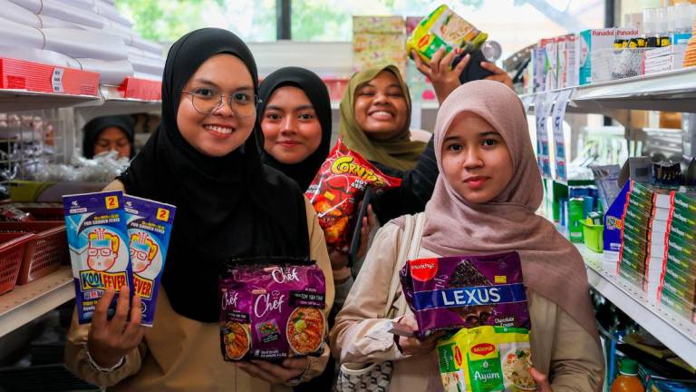 Penuntut Universiti Teknologi MARA (UiTM) Dungun Erina Natasha Mohd Saufi, 23, (kiri) bersama rakan menunjukkan bararangan keperluan harian yang dibeli menerusi Program Jualan Rahman MADANI (PJRM) @Kampus di UiTM Dungun, hari ini - BERNAMA