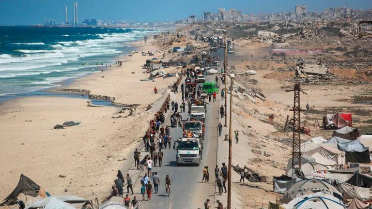 Palestinians carrying belongings arrive on a coastal path northwest of Nuseirat refugee camp as they are displaced southward from Wadi Gaza following an Israeli announcement of closing Al-Rashid road towards the north of the besieged Gaza Strip on October 1, 2025. - Bashar TALEB / AFP