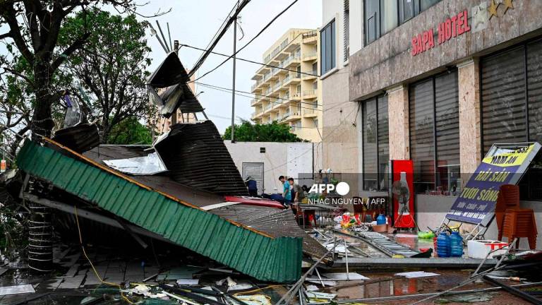 Workers clear the debris of a collapsed corrugated iron roof near Cua Lo beach after Typhoon Kajiki passed through Nghe An province on August 26, 2025. - Nhac NGUYEN / AFP