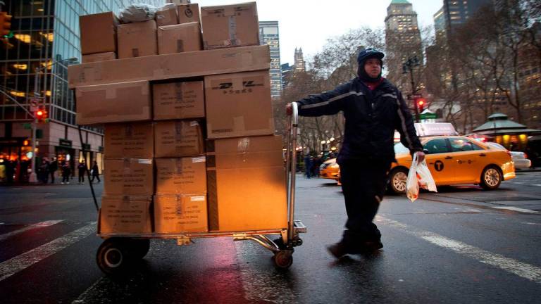 FILE PHOTO: A delivery person wheels a trolley full of packages across 42nd Street in New York December 2, 2014. REUTERS/Carlo Allegri/File Photo/File Photo