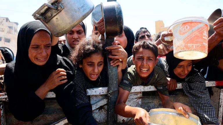 Palestinians receive lentil soup at a food distribution point in Gaza City on August 2, 2025. The World Health Organisation warned on July 27 that malnutrition was reaching “alarming levels” in Gaza. - Omar AL-QATTAA / AFP
