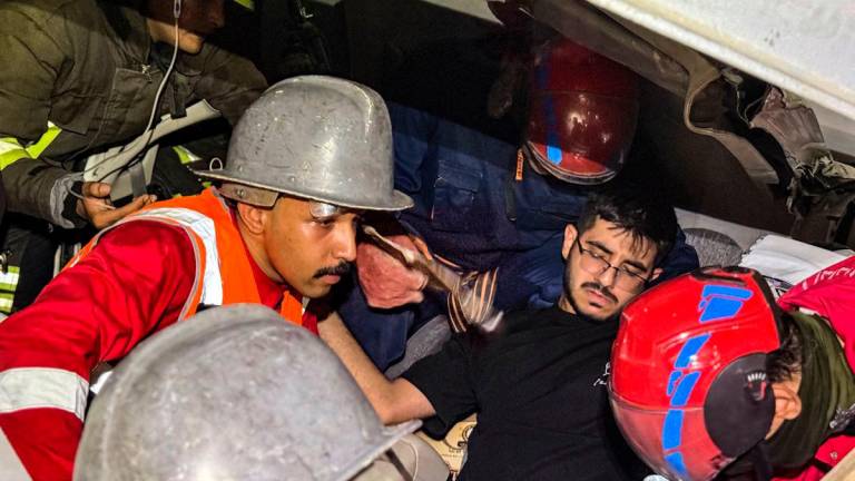 Rescuers retrieve a man from the wreckage of a section of a bridge under construction after it collapsed, killing two people and injuring others, in Karbala in southern Iraq late on September 6, 2025. Rescue workers laboured until morning to free those trapped in their vehicles under the twisted wreckage of the bridge on the main Karbala-Baghdad road. (Photo by Salman AMIN / AFP)