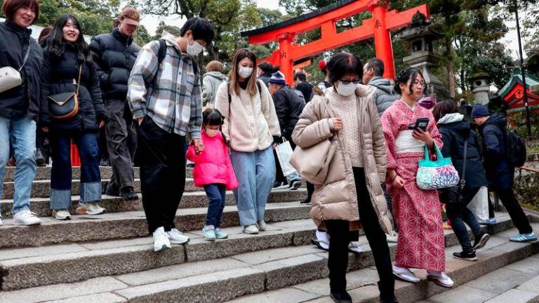 Tourists walk down steps during a visit to Fushimi Inari Shrine in the city of Kyoto on January 13, 2025. - AFPPIX