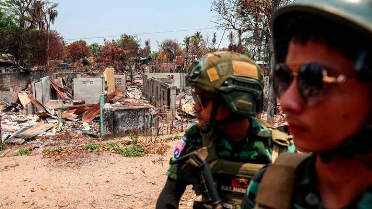 Soldiers from the Karen National Liberation Army (KNLA) patrol on a vehicle, next to an area destroyed by Myanmar's airstrike in Myawaddy, the Thailand-Myanmar border town under the control of a coalition of rebel forces led by the Karen National Union, in Myanmar, April 15, 2024. - REUTERSPIX