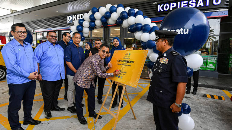 FAMA Director-General Abdul Rashid Bahri (second from right) signing a plaque to symbolise the official launch of the Kopiesatu Outlet at Petron Pedas, today. – BERNAMA