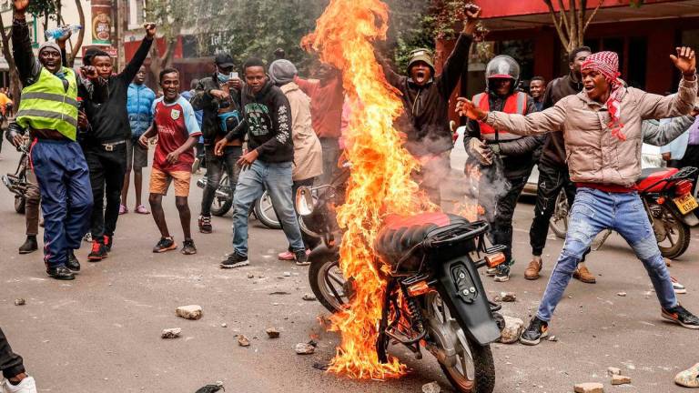 Demonstrators react near a burning motorbike during a protes in nairobi on June 17, 2025. (Photo by SIMON MAINA / AFP)