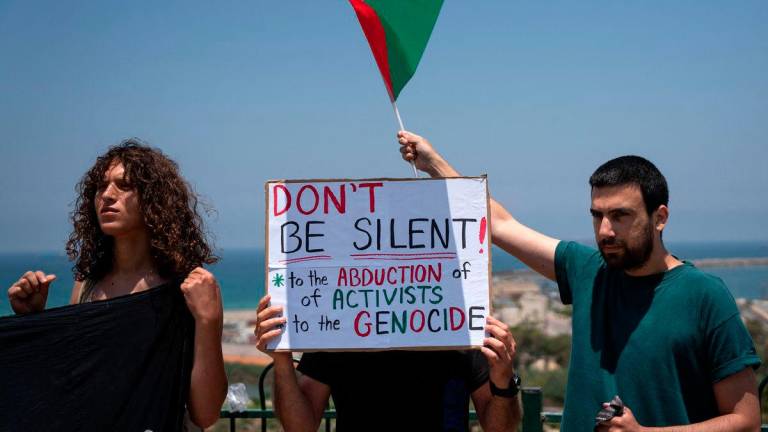 Protesters hold placards and the Palestinian flag during a gathering near the Israeli port of Ashdod on June 9, 2025, after Israeli forces intercepted a Gaza-bound aid boat. Israeli forces intercepted a Gaza-bound aid boat on June 9, preventing the activists on board -- including Swedish campaigner Greta Thunberg -- from reaching the blockaded Palestinian territory. (Photo by MAYA LEVIN / AFP)