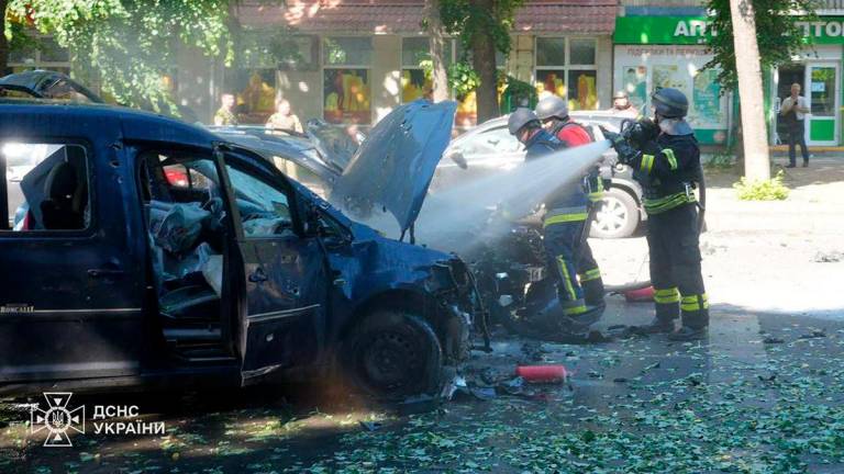 Ukrainian rescuers extinguish a burning car at the site of a missile attack in Sumy, amid the Russian invasion of Ukraine. (Photo by Handout / UKRAINIAN EMERGENCY SERVICE / AFP)