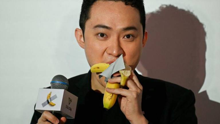 Chinese-born crypto founder Justin Sun eats a banana artwork composed of a fresh banana stuck to a wall with duct tape, in Hong Kong on November 29, 2024, after buying the provocative work of conceptual art by Italian artist Maurizio Cattelan at a New York auction for $6.2 million. - AFPPIX