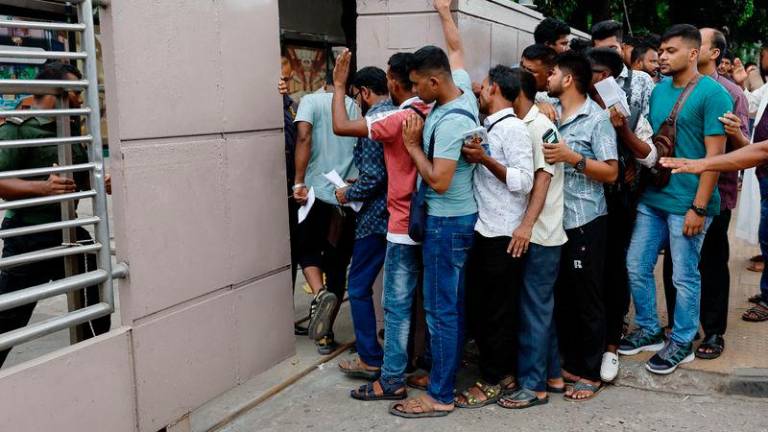 Migrant workers stand in queue to purchase air-tickets of Saudi Airlines on the second-day of curfew, as violence erupted in parts of the country after protests by students against government job quotas, in Dhaka - REUTERSpix