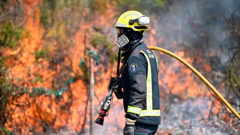 A firefighter works to control a wildfire near the village of Mougas, in Oia municipality, northwestern Spain on August 22, 2025. (Photo by MIGUEL RIOPA / AFP)