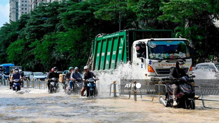 Motorcyclists and vehicles drive on a flooded street in Hanoi on October 2, 2025. Persistent heavy rain in the days after Typhoon Bualoi landed in Vietnam has brought widespread flooding to the capital Hanoi. - AFP