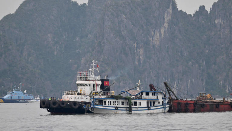 Bot pelancong (C) yang terbalik telah ditunda kembali ke pelabuhan di Teluk Hạ Long, Wilayah Quảng Ninh pada 20 Julai 2025. - AFP
