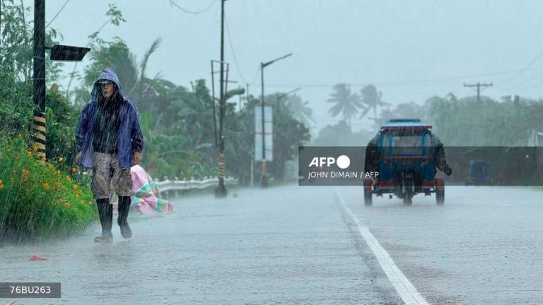 A man walks along a road amid heavy rain due to weather patterns from Super Typhoon Ragasa in Lal-lo town, Cagayan province on September 22, 2025. - AFP