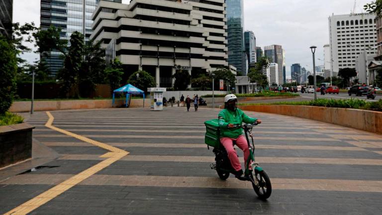 A driver working for the ridesharing company Grab wears a protective mask at a sidewalk near the business district, on the first business day of the New Year, in Jakarta, Indonesia, January 4, 2021. REUTERSpix