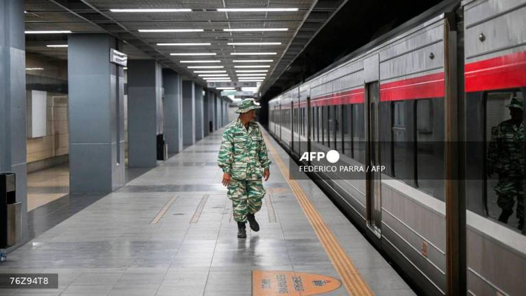 A member of the Bolivarian militia inspects an evacuated train station during a risk reduction drill on natural disasters or armed conflict in Caracas on September 27, 2025. (Photo by Federico PARRA / AFP)
