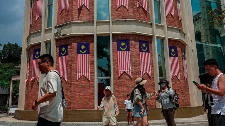 Foreign tourists stroll around Dataran Merdeka with buildings adorned with the Jalur Gemilang in the background, ahead of the National Day and Malaysia Day (HKHM) 2025 celebrations. – BERNAMA