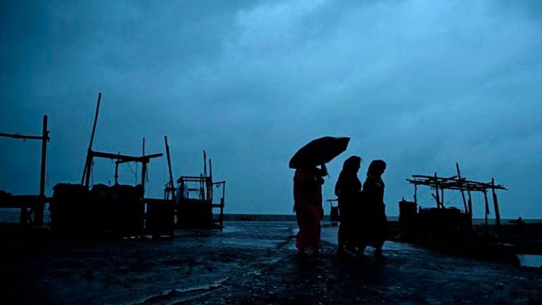 Villagers walk along a beach near Digha on October 24, 2024, as cyclone Dana is likely to hit the coasts of West Bengal and Odisha states. - AFPPIX