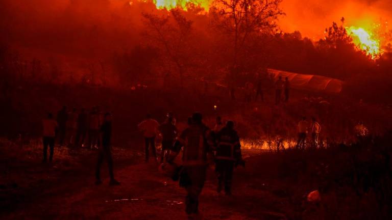 Residents and firefighters attempt to extinguish a wildfire as smoke and flames rise from a forested area in the Gursu district of Bursa early on July 27, 2025. (Photo by ONUR YURTSEVER / AFP)