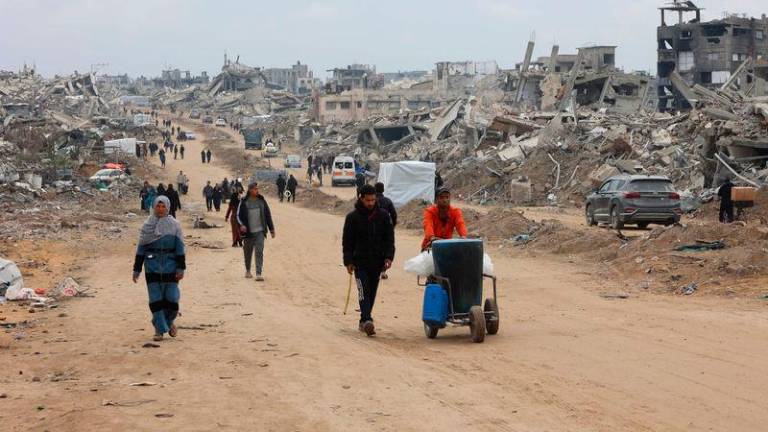 Palestinians walk past collapsed buildings along Saftawi street in Jabalia in the northern Gaza Strip - AFPpix