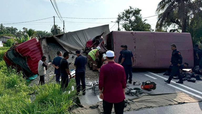 This handout photo taken and released by Perak's Fire and Rescue Department on May 13, 2025 shows rescuers searching for survivors after a lorry collided with a truck carrying members of the Malaysian paramilitary force Federal Reserve Unit (FRU) in Teluk Intan in Malaysia's Perak state. - AFPPIX