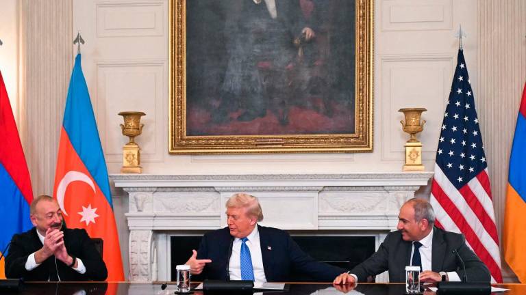 US President Donald Trump (C), Azerbaijani President Ilham Aliyev (L) and Armenian Prime Minister Nikol Pashinyan react after signing an agreement in the State Dining Room of the White House in Washington, DC on August 8, 2025. - ANDREW CABALLERO-REYNOLDS / AFP