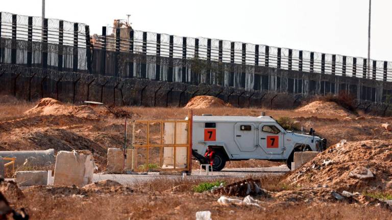 A Gazan man sits next to a gate and an armored vehicle by the Philadelphia road near Kerem Shalom crossing where parcels of humanitarian aid await to be transferred into Gaza from Israel, July 24, 2025. - REUTERSPIX